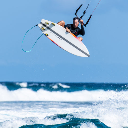 Man performing a high jump while kiteboarding over ocean waves using the Burner XR V1 board with a One-Lock modular system for versatile performance.