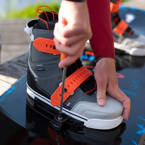 Close-up of a person securing the 2024 RAD boot onto a foil board using a screwdriver, highlighting the technical setup and One-Lock modular system features.