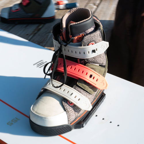 Close-up of a 2024 Zuupack wakeboard boot secured with adjustable straps on a white wakeboard, showing durable materials and rider-focused design for high performance water sports.
